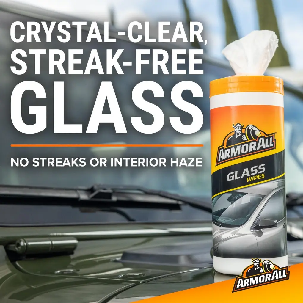 A hand cleaning a car dashboard with an Armor All Protectant wipe