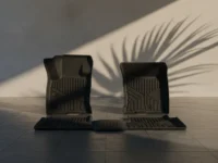 Tapetes pretos premium Michelin Bronco Sport contra parede minimalista com sombra de folha de palmeira.