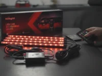 A hand controls Nilight 4PCS Car Interior Lights with a remote on a table.