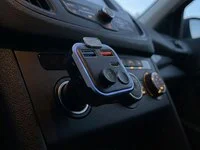 A small plug-in adapter with a soft blue ring light in a car dashboard power socket at dusk